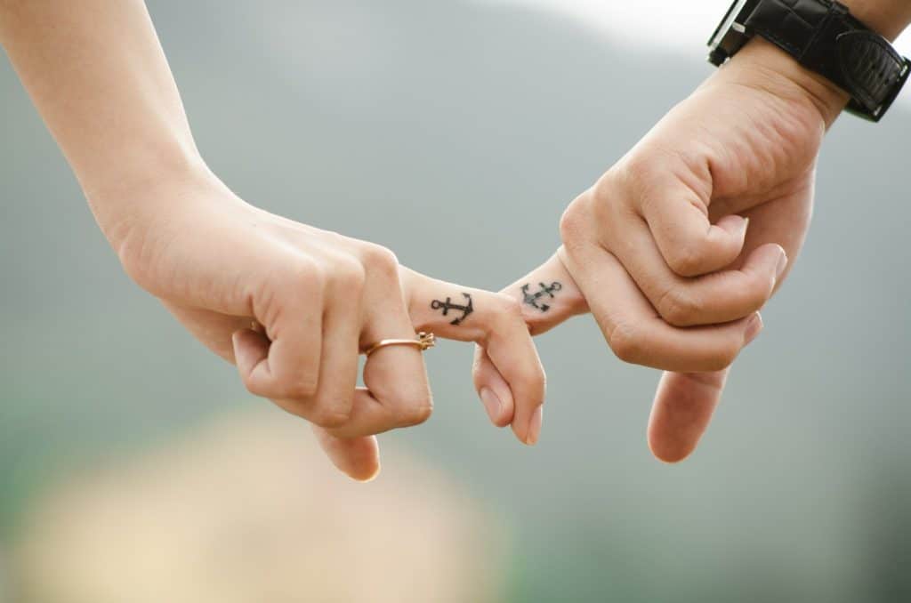 Deux mains liées ayant chacune une petit tatouage d'ancre marine