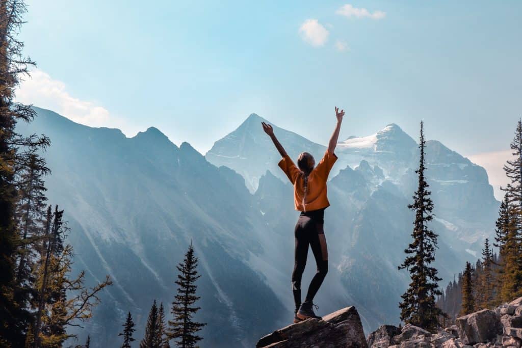 Femme sportive qui lève les bras en signe de victoire face à un paysage montagneux